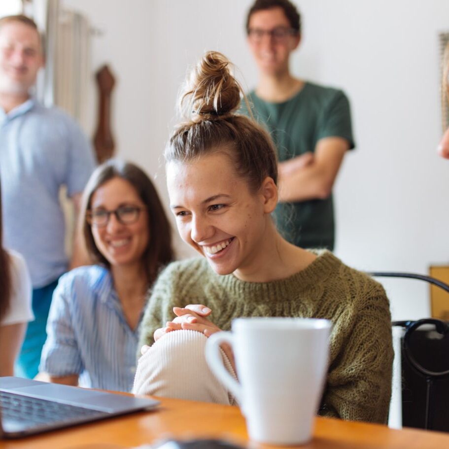 Group of size people laughing around laptop